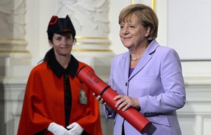 German Chancellor Angela Merkel (R) smiles after she received a docteur honoris diploma at the University of Swiss capital Bern on September 3, 2015. Germany and France have agreed that the European Union, facing a slew of migrant crises, should impose binding quotas on the numbers member states take in, German Chancellor Angela Merkel said Thursday. AFP PHOTO / FABRICE COFFRINI