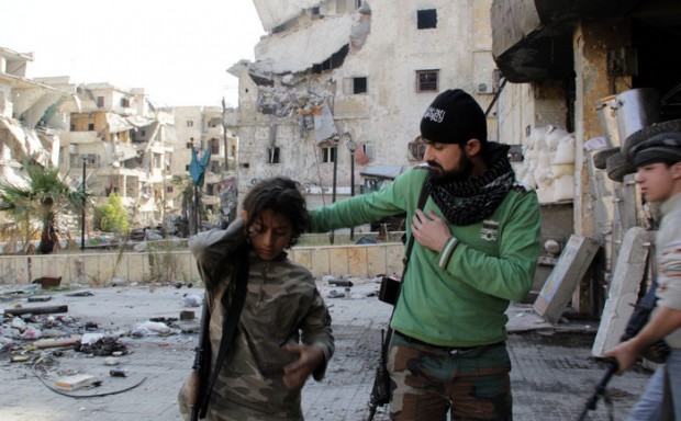 Syrian youth Ahmed, 13-years old (L) and Faris (R), 16-years old, who allegedly fight alongside opposition fighters from the Sadeq Al-Amin Brigade, get prepared with another member of the brigade before a patrol in the Salah al-Din neighbourhood of the northern Syrian city of Aleppo on November 17, 2013. For three weeks, the army has been pressing a campaign to retake rebel-held areas in Aleppo, particularly east of the country's second city, and jihadist fighters have called for mass mobilisation to counter regime advances. AFP PHOTO / KARAM AL-MASRI (Photo credit should read KARAM AL-MASRI/AFP/Getty Images)