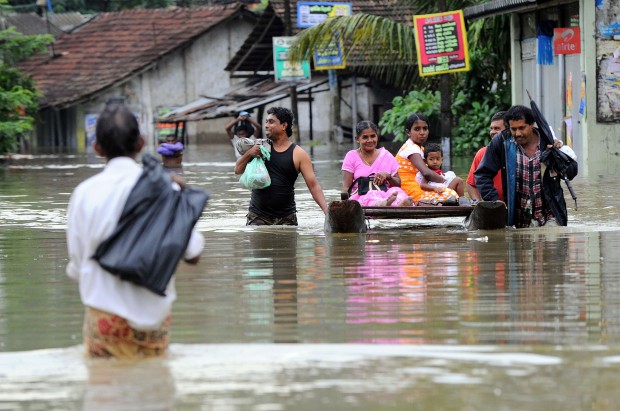 TOPSHOTS Sri Lankan residents wade through floodwaters in Welipanna on June 2, 2014. Mudslides cause by heavy monsoon rains in the west and south of the island have killed at least 13 people and left two more missing. AFP PHOTO / Ishara S. KODIKARAIshara S.KODIKARA/AFP/Getty Images